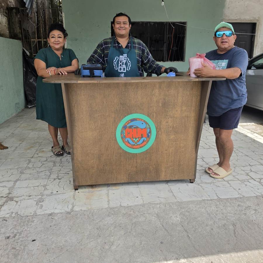 La familia de Chumi detrás de su mostrador de madera con el logo pintado a mano